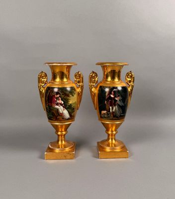 pair of gold vases with paintings on them sitting on a table