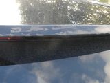 a close up of a car ' s rear window with a reflection of trees in the background