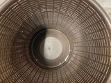 a brown plastic basket sitting on the floor next to a white wall