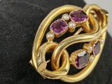 a close up of a gold ring with purple stones on a black surface