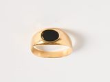 gros plan d'une bague en or avec une pierre noire