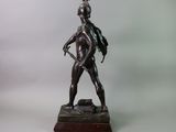 bronze statue of a man with a bow and a hat on a base