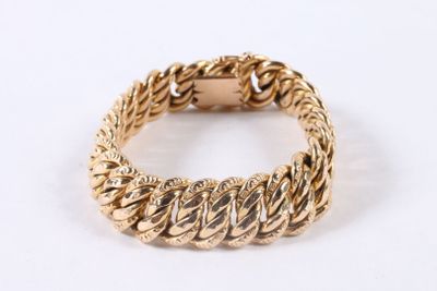 a close up of a gold bracelet on a white surface