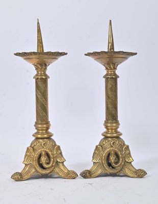 pair of antique brass candlesticks on pedestals against a white background