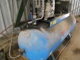 a blue air compressor sitting on a cart in a garage