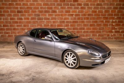 a silver sports car parked in front of a brick wall