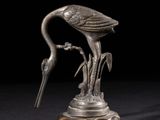une statue en argent représentant un oiseau au long bec, posée sur un socle