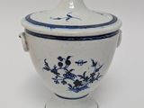 a blue and white bowl with a lid on a white table
