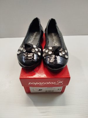une paire de chaussures noires pour femme ornées de nœuds, posée sur une boîte rouge