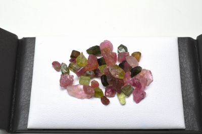 un tas de tourmalines roses et vertes posées sur une surface blanche