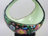 green and black bowl with flowers on it on a clear base