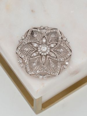une broche en argent posée sur une surface en marbre blanc