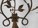 a metal candle holder with flowers and leaves on it