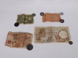 several different bank notes and coins sitting on a white surface