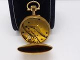 an image of a gold pocket watch sitting on top of a black case