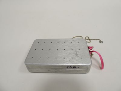 an old metal box with a pink ribbon on a white surface