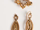 deux paires de boucles d'oreilles et une broche posées sur un fond blanc