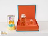 an orange box with two bottles of perfume and a canister