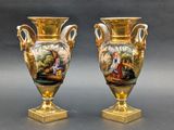 une paire de vases en or ornés de scènes peintes, posés sur une table