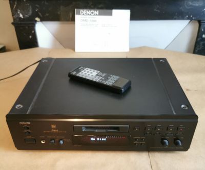 une télécommande posée sur un lecteur CD, lui-même posé sur une table