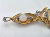 an oplite and diamond broochle is displayed on a white surface