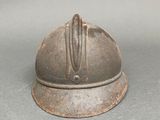 a small metal helmet on a table with a gray background