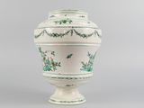 a white vase with green designs on it on a gray surface
