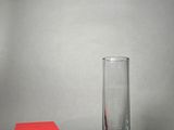 a red box next to a tall glass on a table