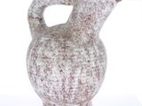 un vase blanc et marron muni d'une anse, posé sur une table