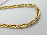 gros plan d'un bracelet en chaîne en or sur une surface blanche