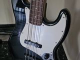 a black and white electric bass guitar on a stand