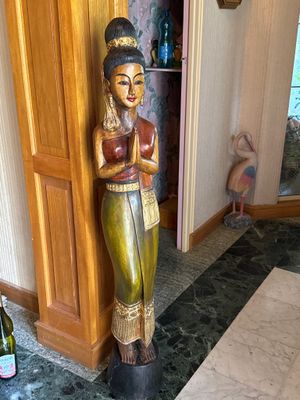 une statue en bois représentant une femme tenant une bouteille de vin