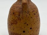 a brown vase that is sitting on a white surface