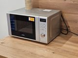 a microwave sitting on a wooden table with a cup on top of it