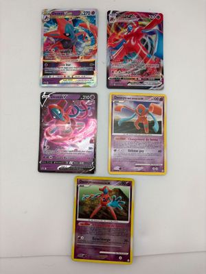 quatre cartes Pokémon différentes sont posées sur une surface blanche