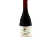 the bottle of red wine is sitting on a white surface