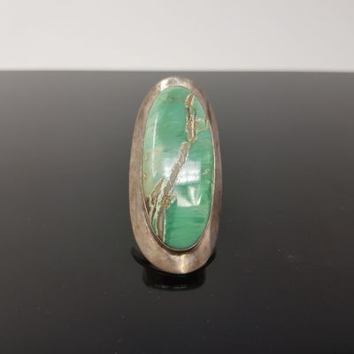 un gros plan d'une bague en argent sertie d'une pierre verte