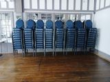 rows of blue plastic chairs in a room with a wooden floor