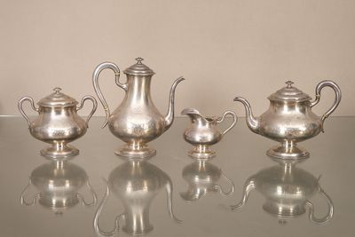 trois théières en argent posées sur une table en verre