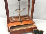 une caisse en bois contenant une balance et une boîte posée par terre
