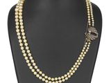 un collier de perles blanches muni d'un fermoir en or, posé sur un mannequin