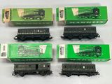 six trains miniatures dans leurs boîtes sont alignés sur une surface blanche