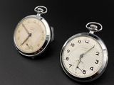 pair of antique pocket watches sitting on a black surface