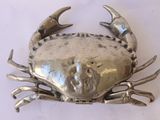 a silver crab that is sitting on a white surface