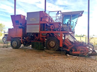 un tracteur rouge garé sur la terre battue