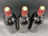 three bottles of red wine are lined up on a table