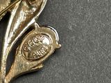 a gold brooch with a bird and a coin on it
