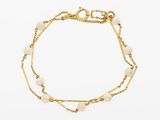 un gros plan d'un bracelet en or orné de perles sur fond blanc