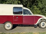 un petit camion rouge et blanc garé sur le bord de la route