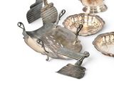 five silver dishes on a white surface with a bird on one of them